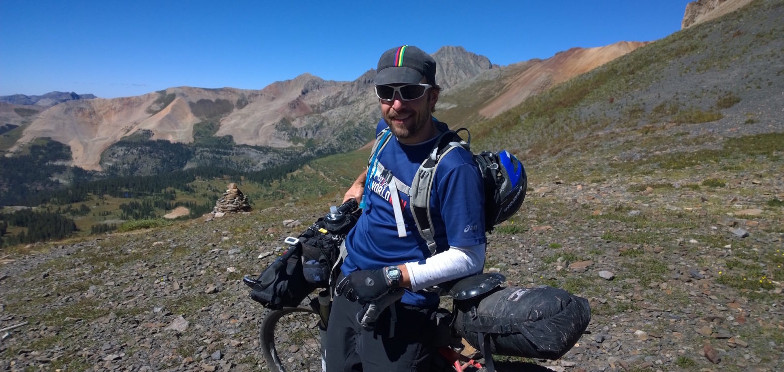 Nick leaning on mountain bike on a high mountain pass